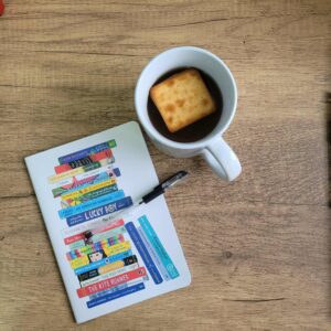 Cup with biscuit floating and notebook and pen